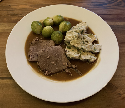 Großmutters Rinderschmorbraten mit Semmelknödeln und Rosenkohl auf den Teller gebracht