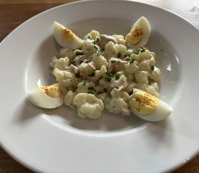 Blumenkohlsalat mit einem Joghurt Dressing, Kochschinken und Ei serviert